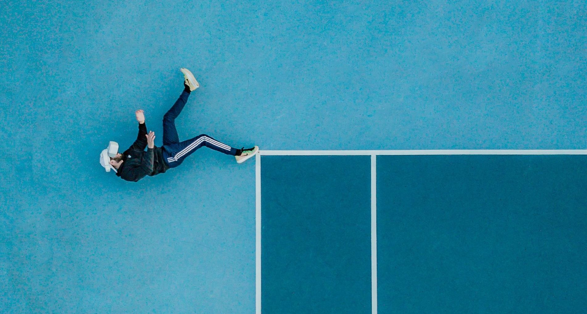 An aerial view of a person falling on a tennis court.
