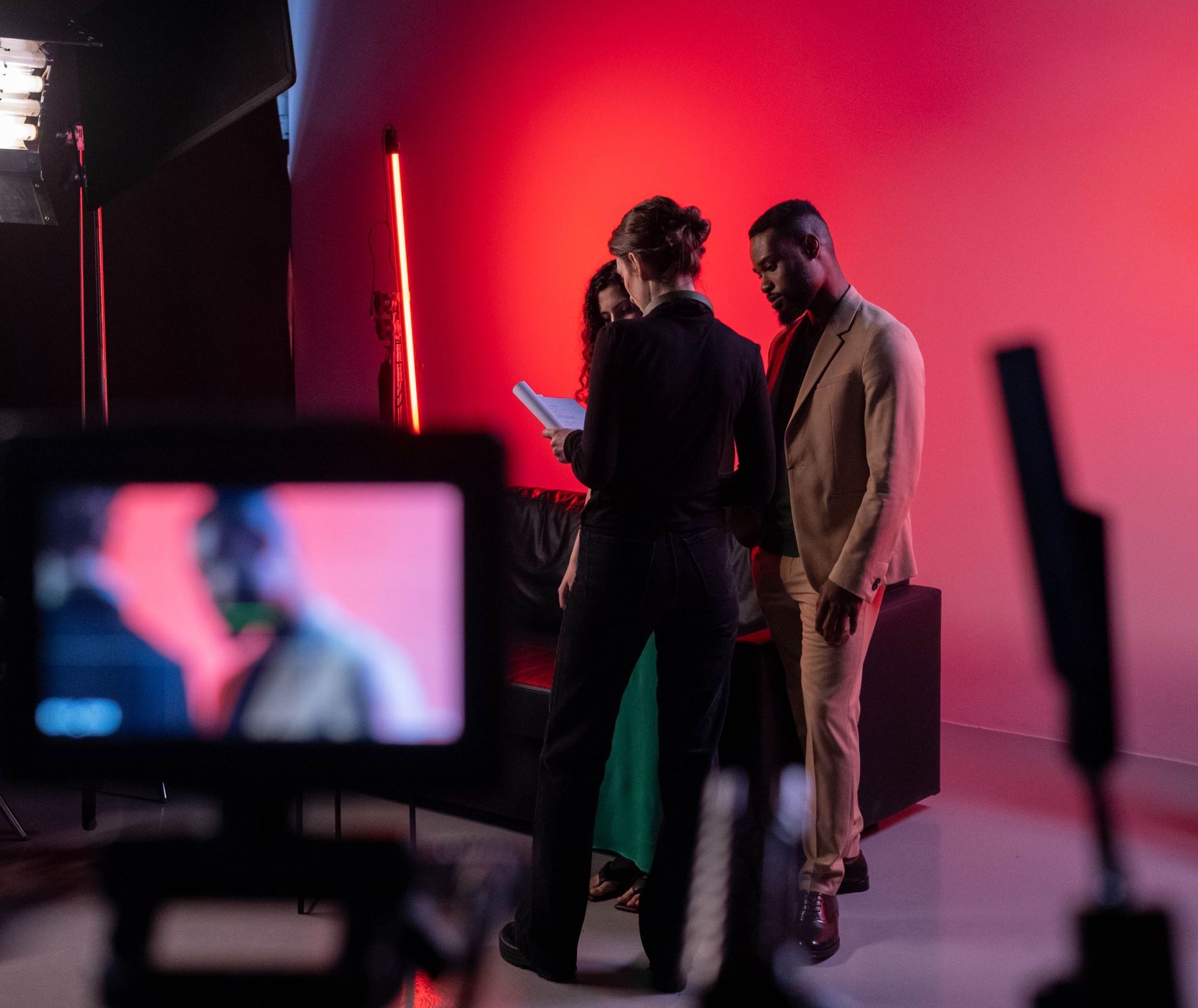 Behind the scenes studio video production shoot Filming a scene with two people and a director in a studio with a camera in the foreground.