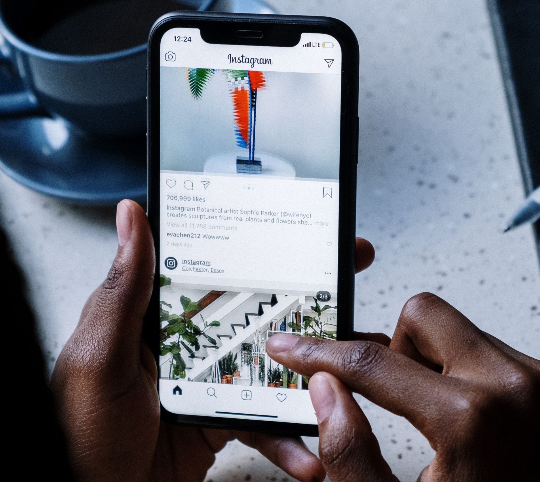 Person holding a smartphone with an Instagram feed open, scrolling through posts.