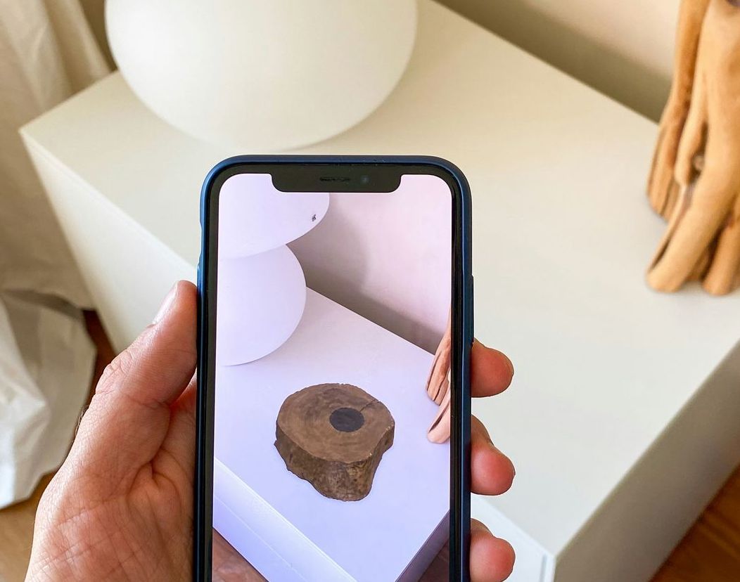 Phone being held up showing Augment Reality on screen A person is holding a cell phone with a picture of a piece of wood on the screen.