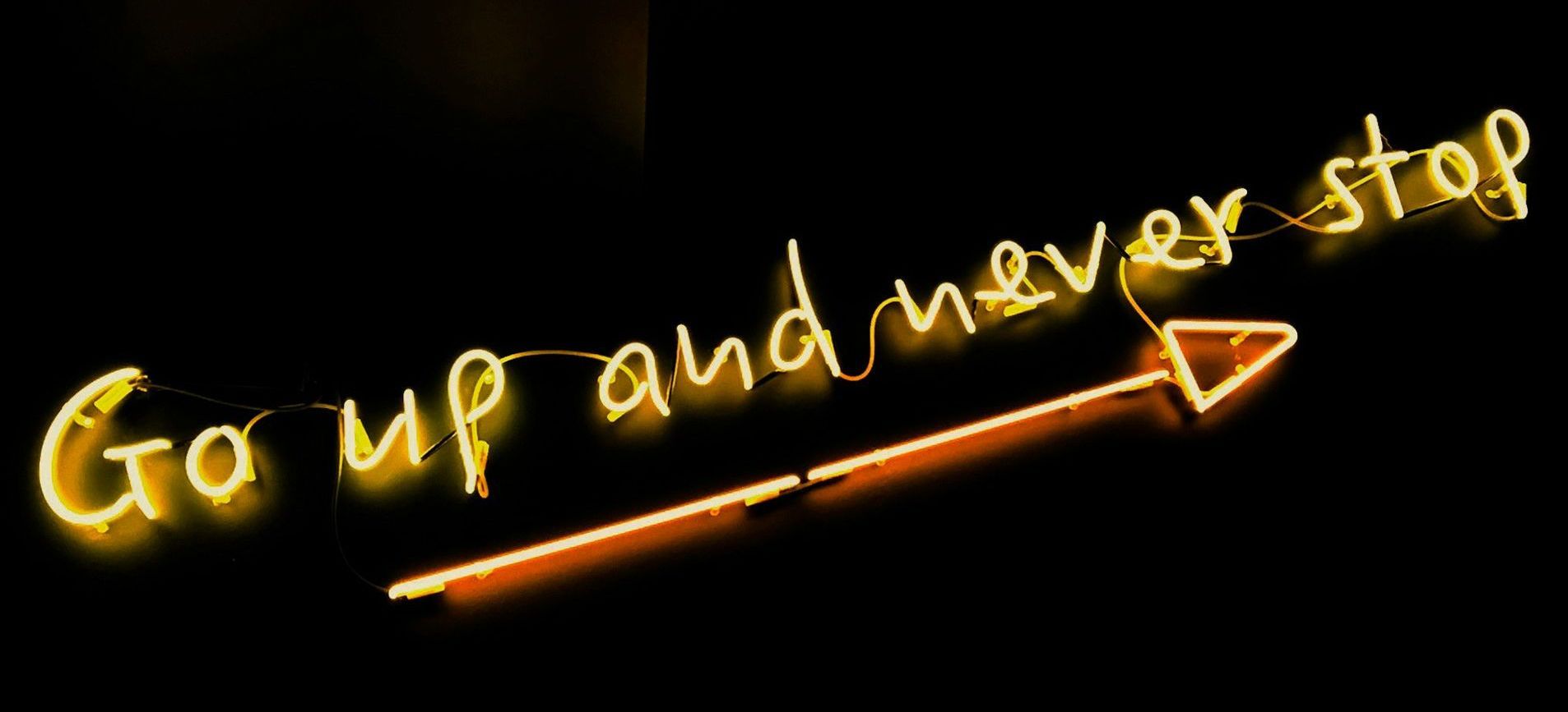 Yellow neon sign on black background reads