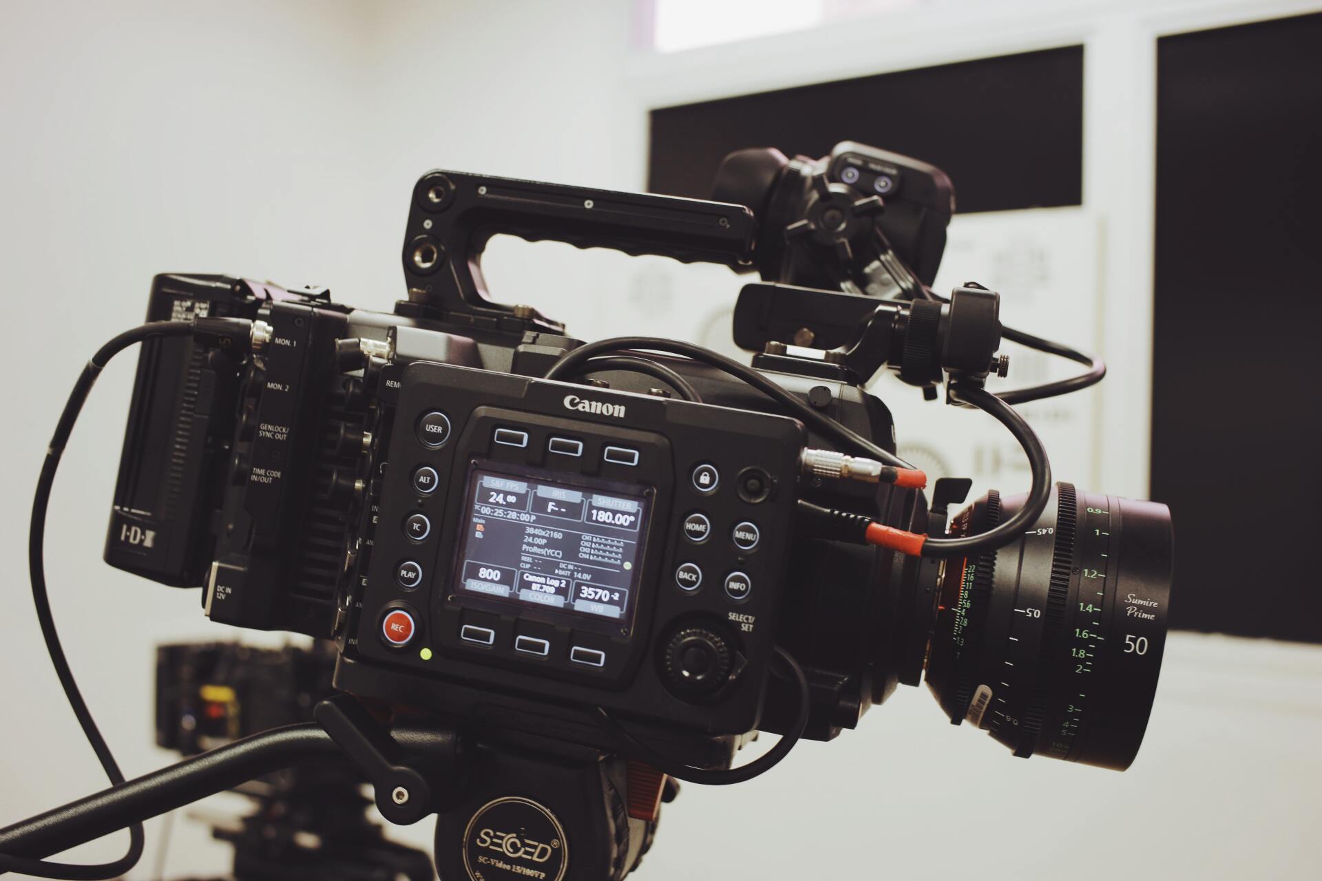 A video camera is sitting on a tripod in a room.