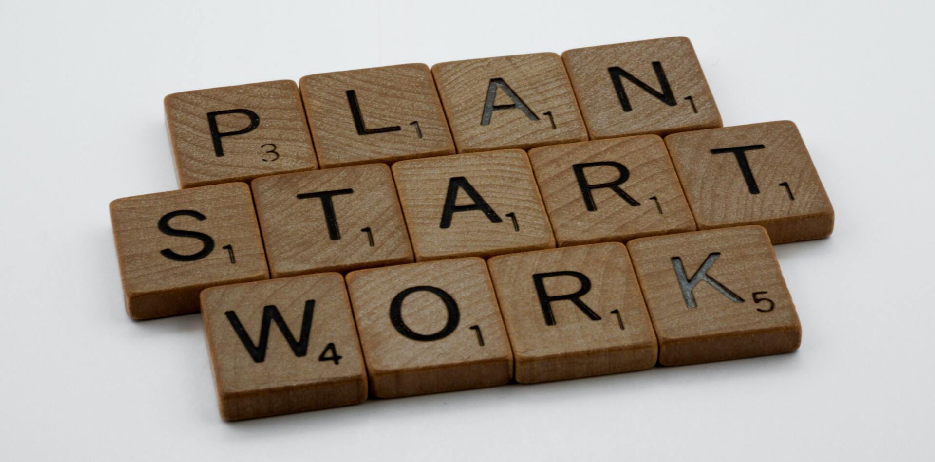Scrabble tiles with the words plan start work written on them
