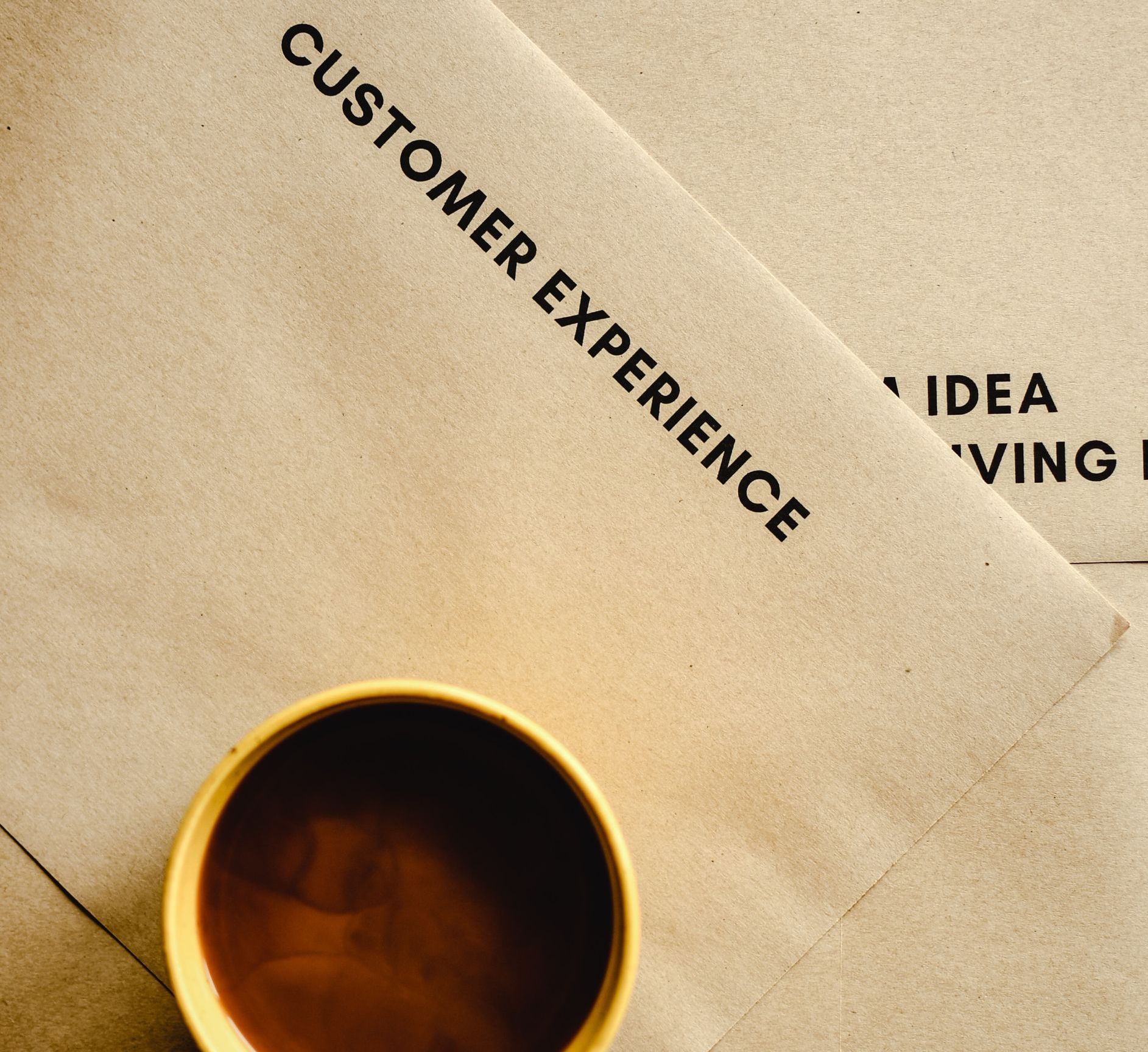 Customer experience printed on paper with coffee cup A cup of coffee sits next to a piece of paper that says customer experience