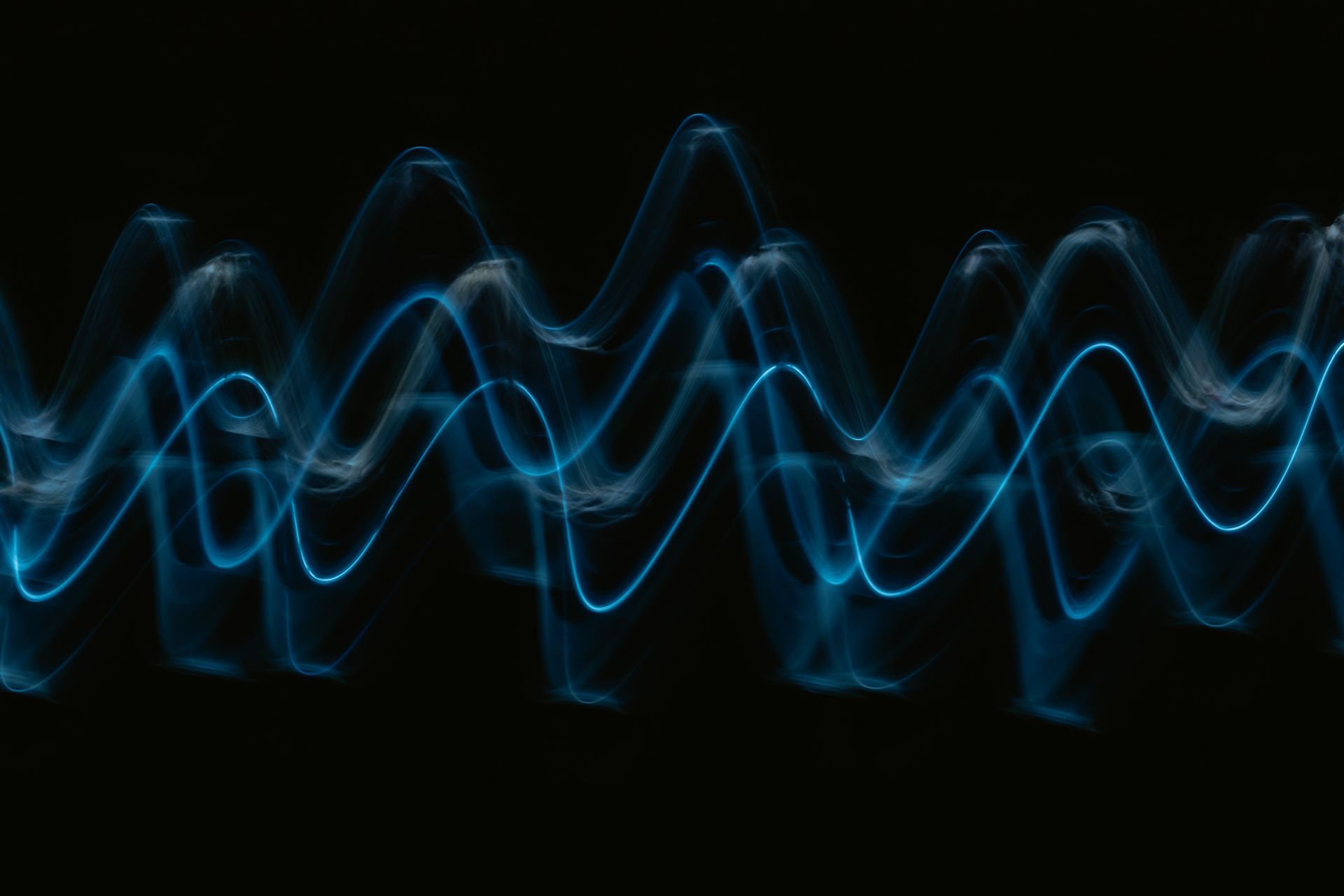 A long exposure photo of a blue light wave on a black background.