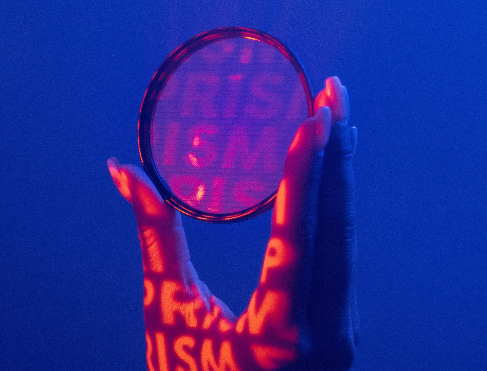A person is holding a lens with the word prism projected on their hands
