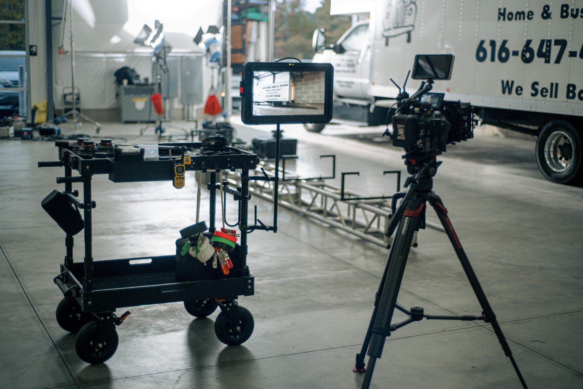 A camera is on a tripod in front of a truck that says home & bus 616-647
