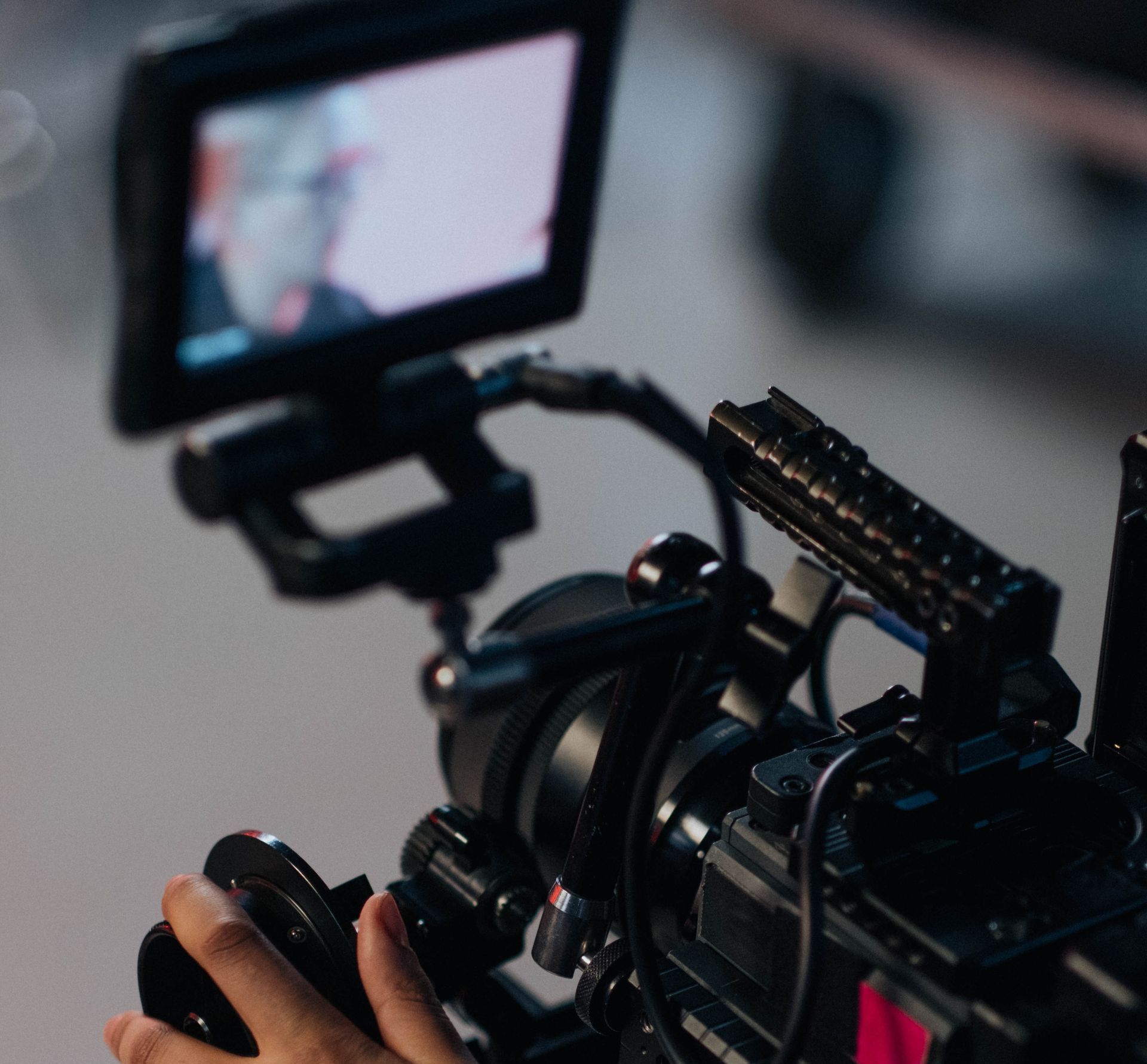 A person is holding a video camera with a monitor attached to it.
