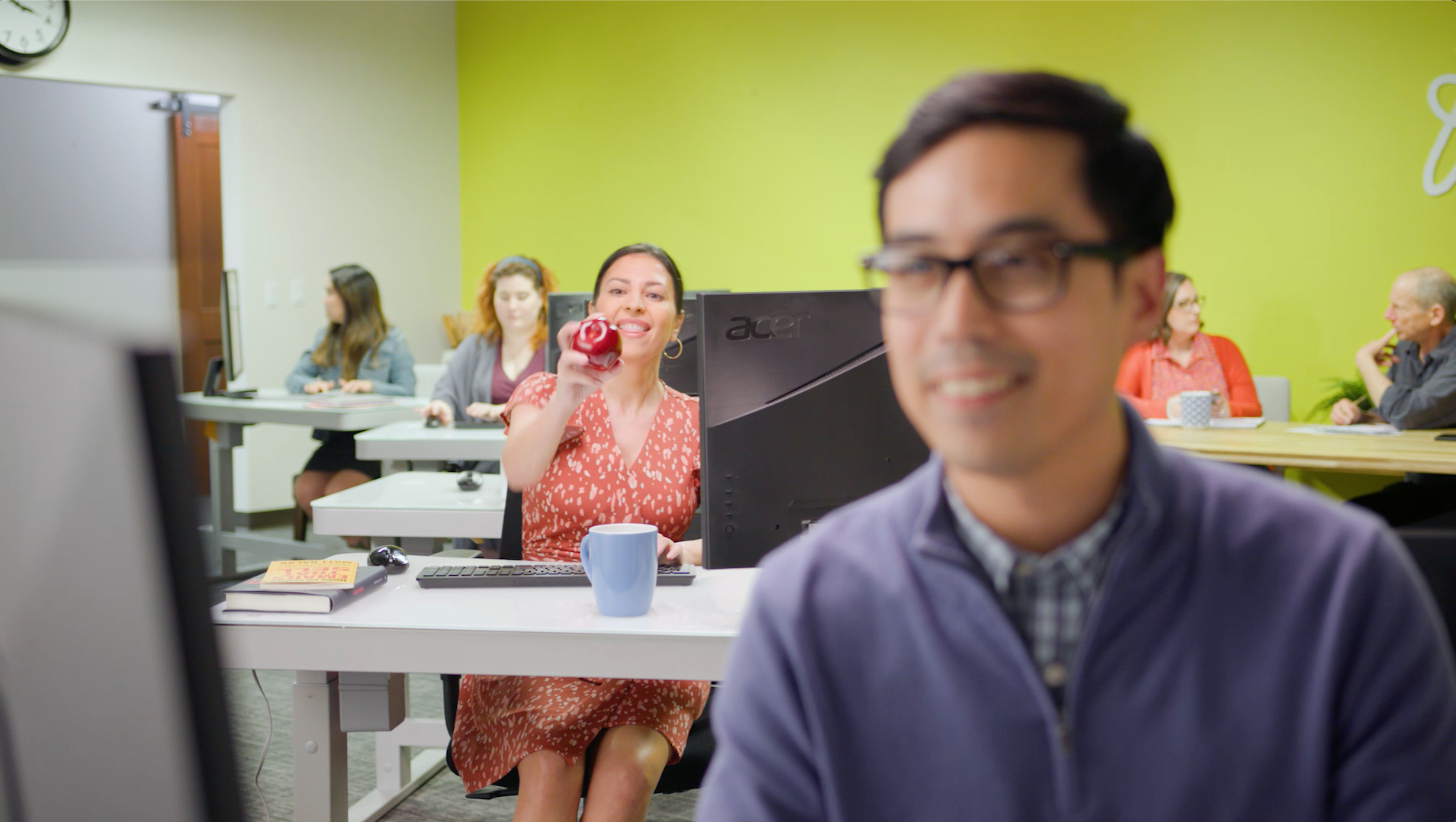A man and a woman are sitting at a desk in front of a computer.