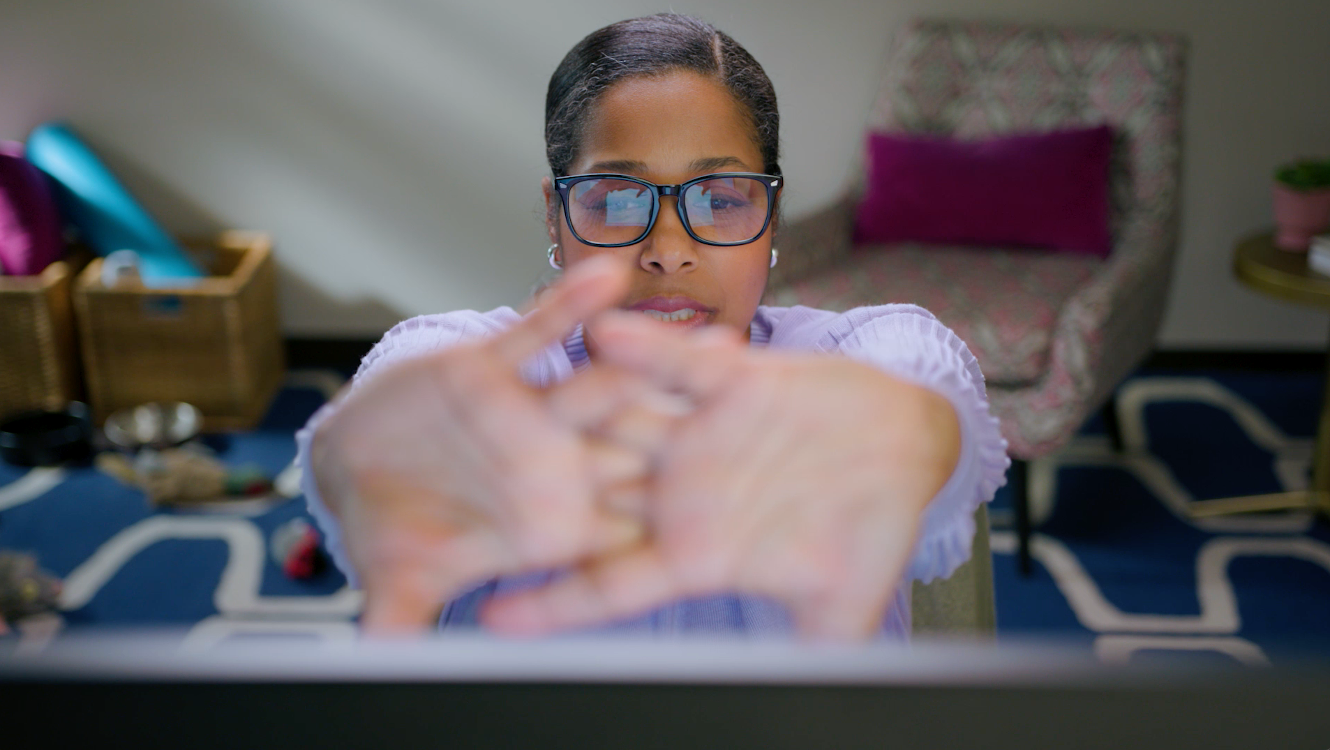 A woman wearing glasses is sitting in front of a laptop computer.