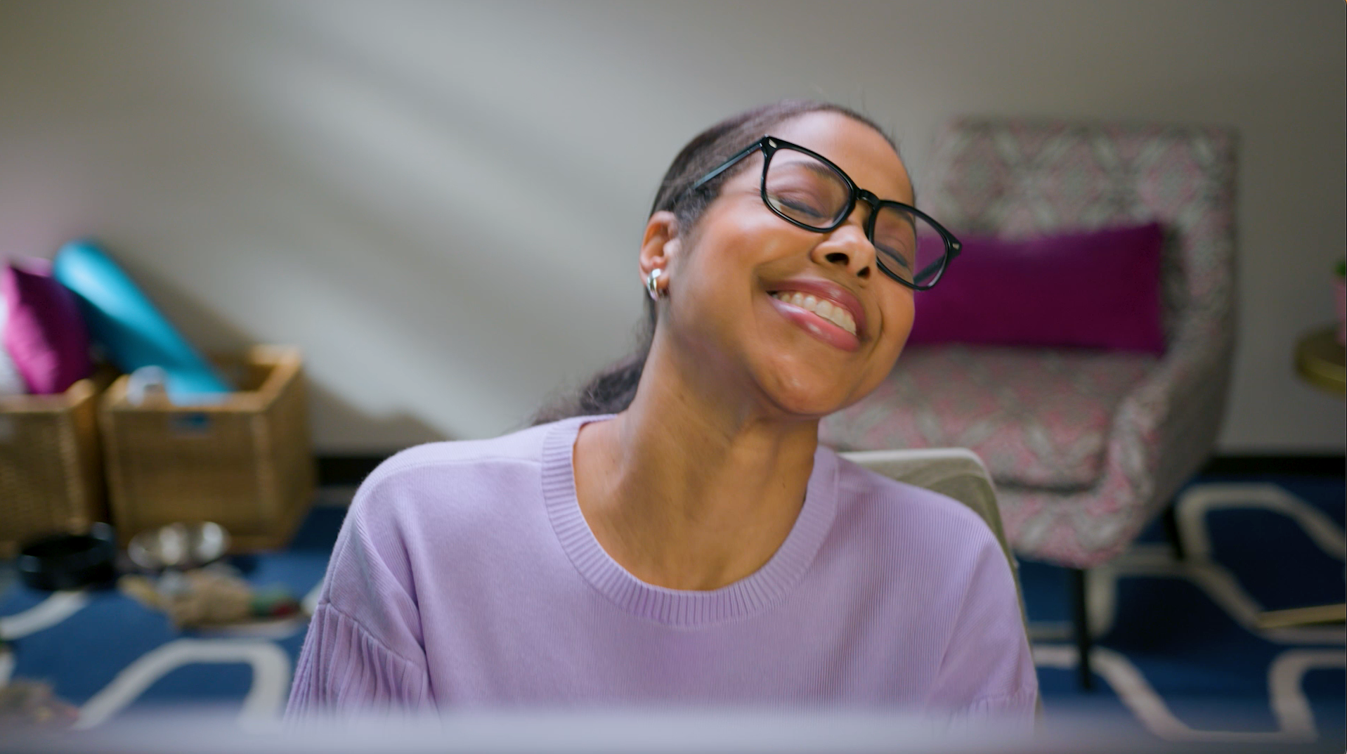 Spin Creative Microsoft Viva Relaunch A woman wearing glasses is smiling while sitting in front of a laptop computer.