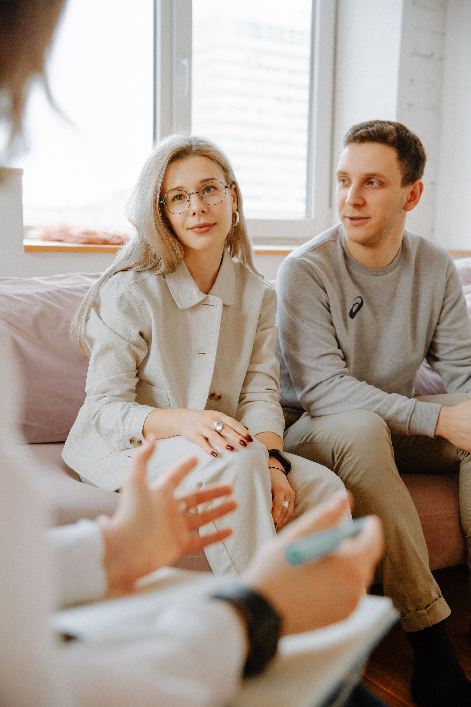 Two people seated in a bright living room, listening during a conversation