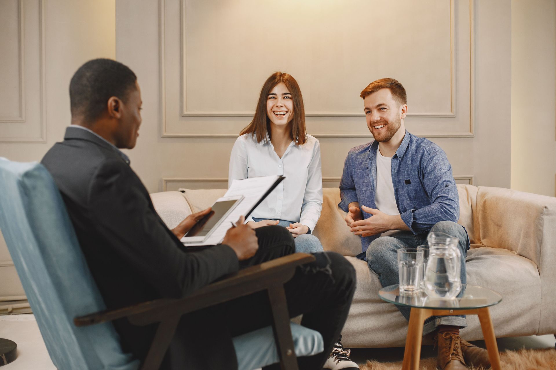 Three people in a counseling session with a therapist in a bright office, seated around a table.