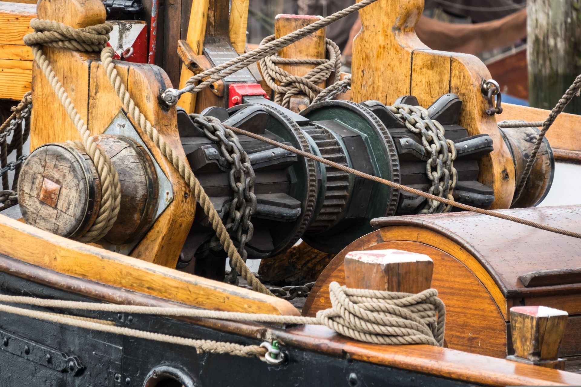 Close-up of a boat winch with chains, rope, and wooden deck fittings