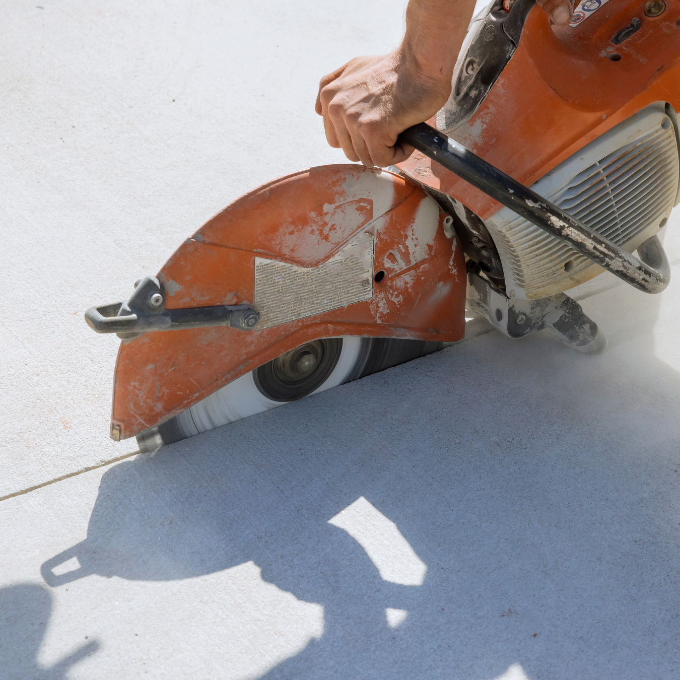 A person is using a stihl saw to cut concrete