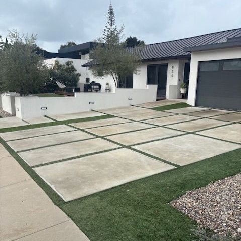 A white house with a black garage door and a concrete driveway