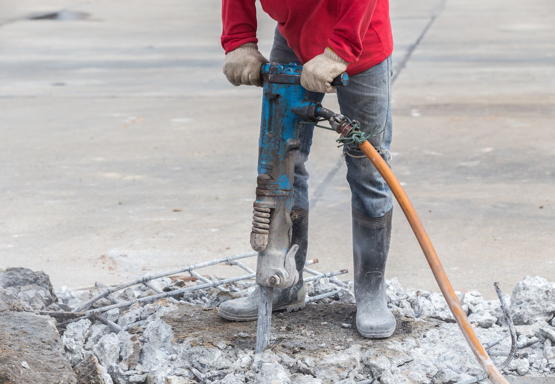 A man is using a hammer to break concrete.