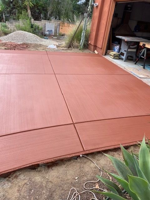A red concrete driveway is being built in front of a garage.