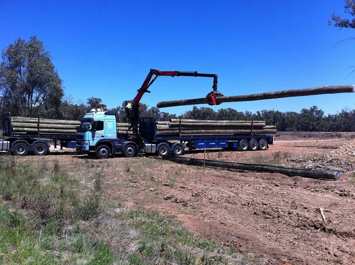 A Truck is Carrying Logs on a Trailer in a Field — Country Powerline Constructions in Mudgee, NSW