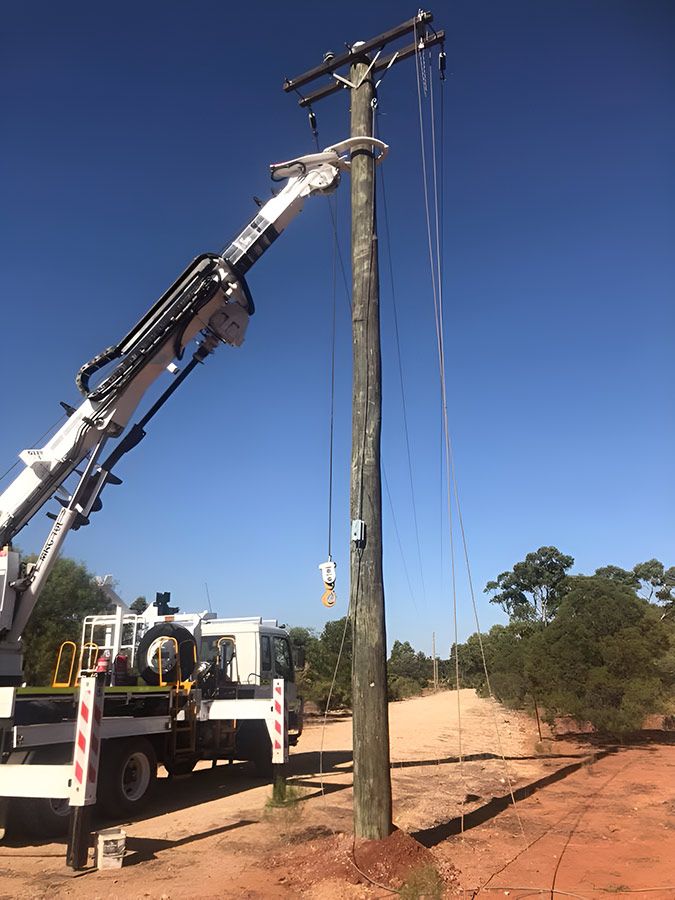 A Truck With a Crane Attached to It is Working on a Power Pole — Country Powerline Constructions in Dubbo, NSW