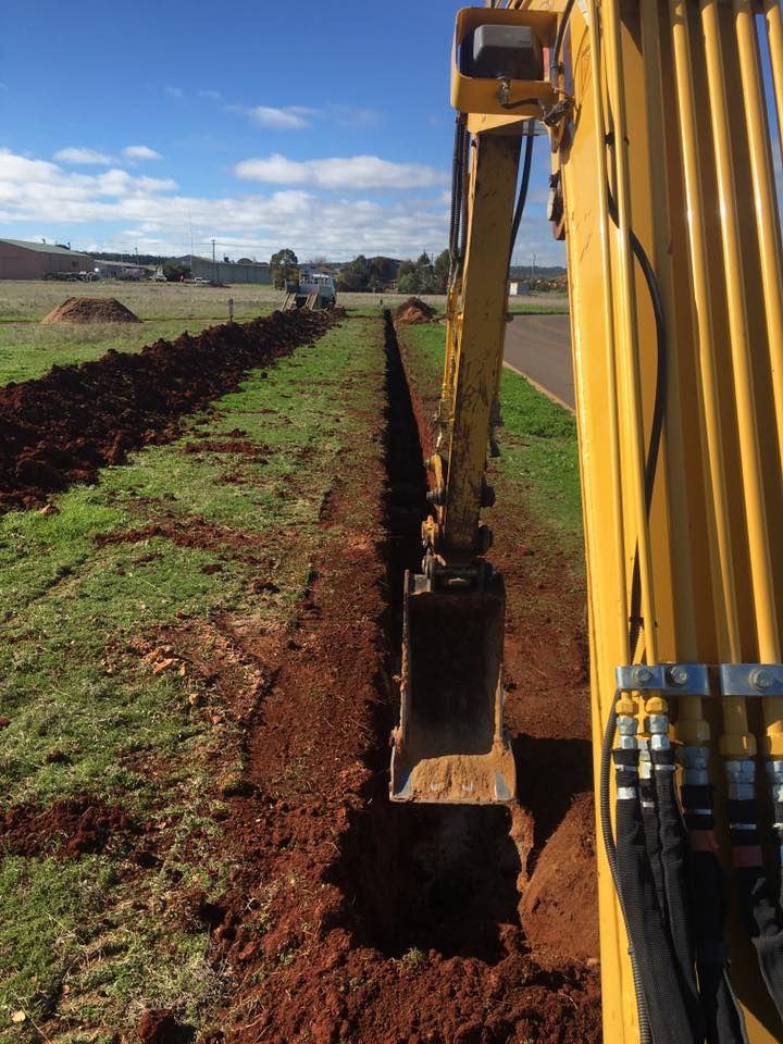 A Yellow Excavator is Digging a Trench in a Field — Country Powerline Constructions in Hunter Valley, NSW