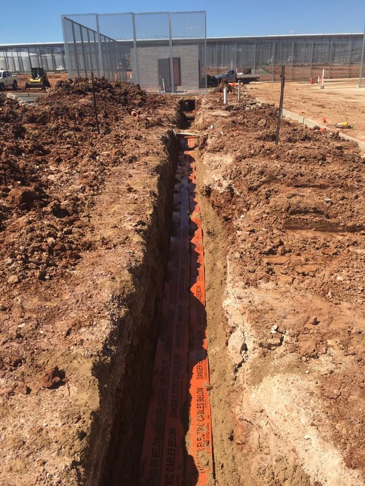 A Trench is Being Dug in the Dirt in Front of a Building — Country Powerline Constructions in Wagga Wagga, NSW