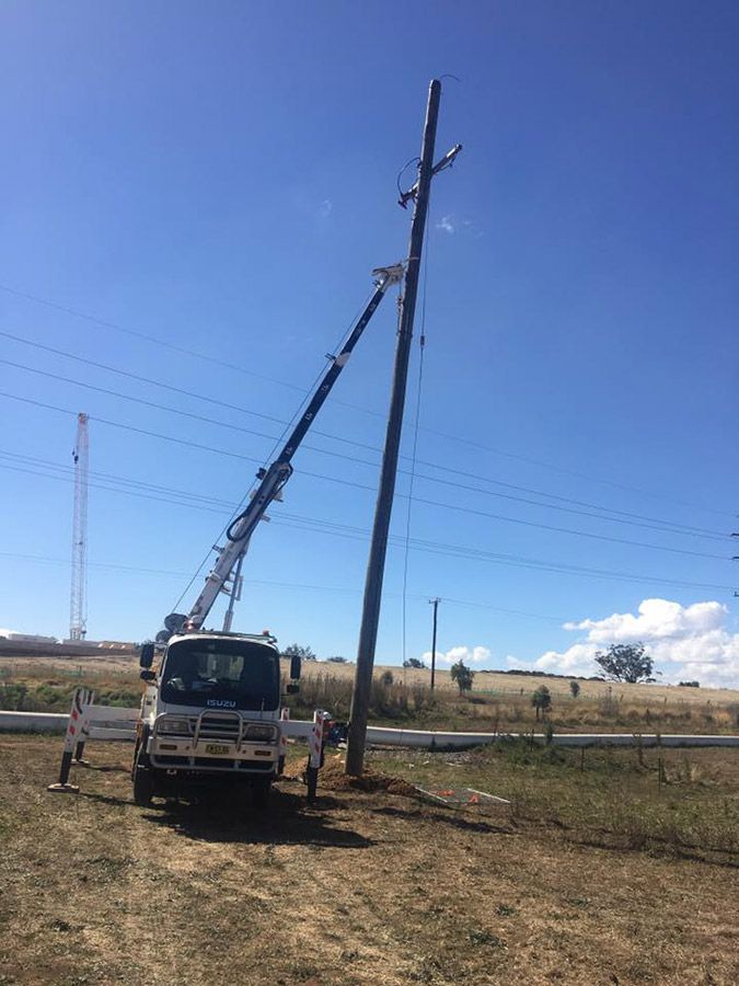 A Truck With a Crane Attached to It is Working on a Power Pole — Country Powerline Constructions in Dubbo, NSW