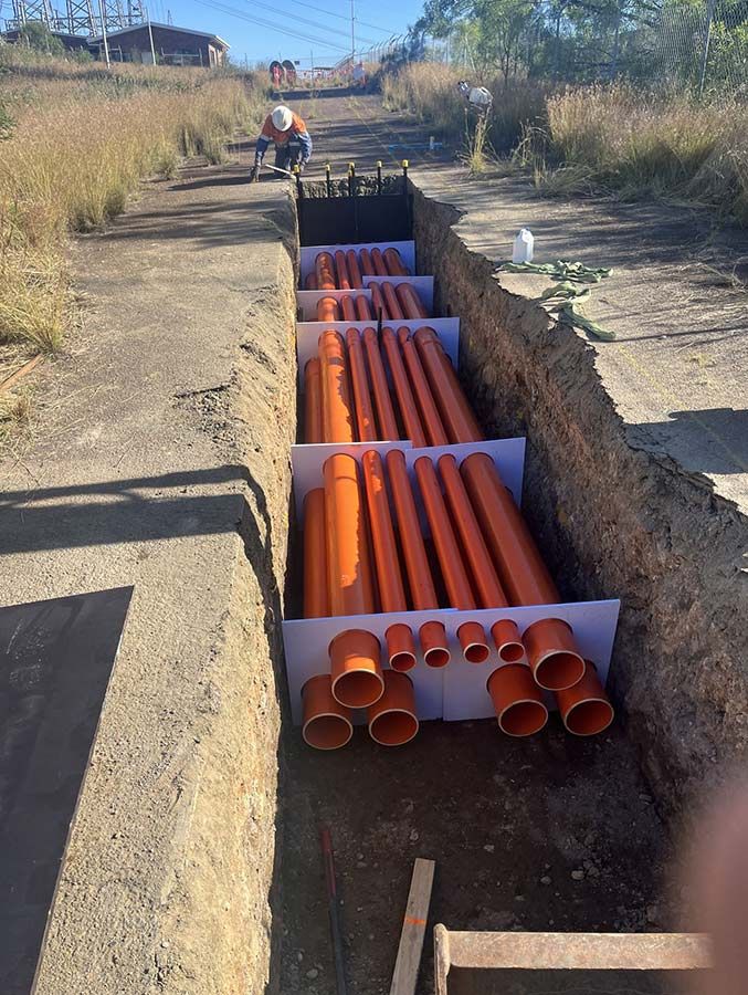 A Bunch of Orange Pipes Are Sitting in a Trench — Country Powerline Constructions in Parkes, NSW