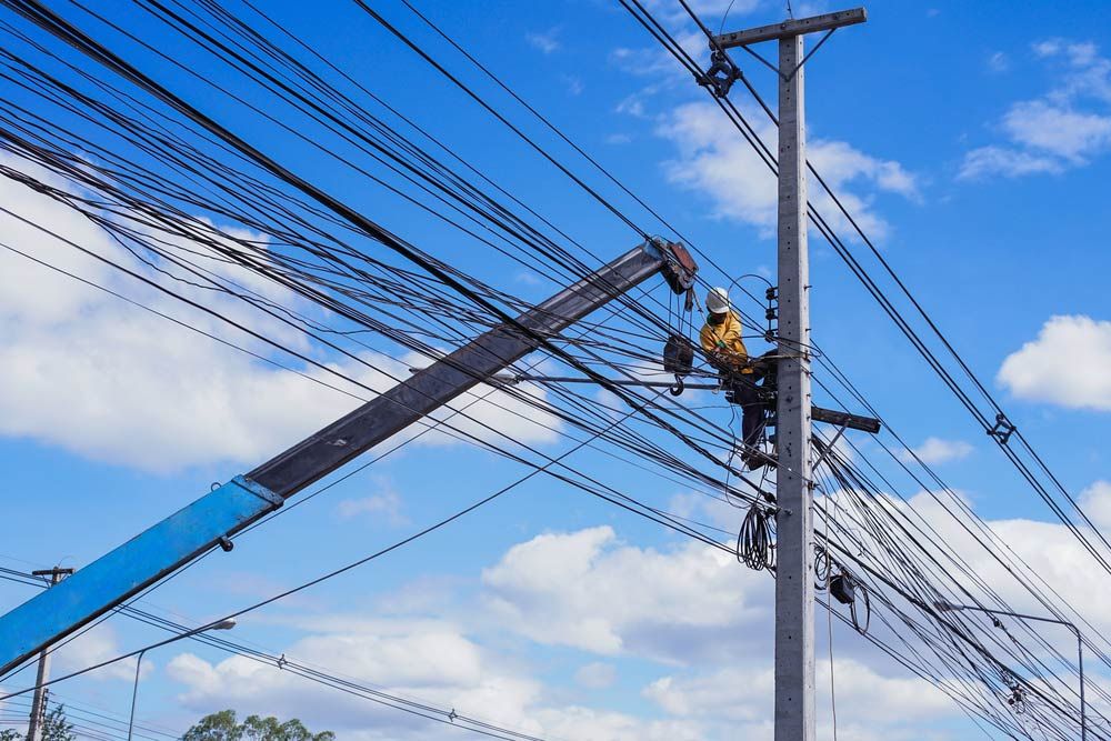 A Man is Working on a Power Pole With a Crane — Country Powerline Constructions in Dubbo, NSW