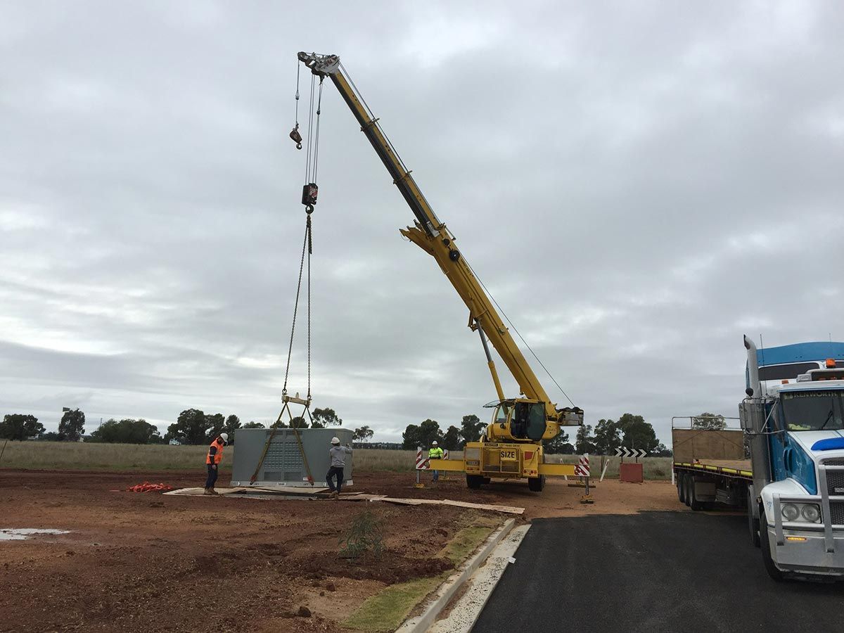 A Large Yellow Crane is Lifting a Large Piece of Metal — Country Powerline Constructions in Dubbo, NSW