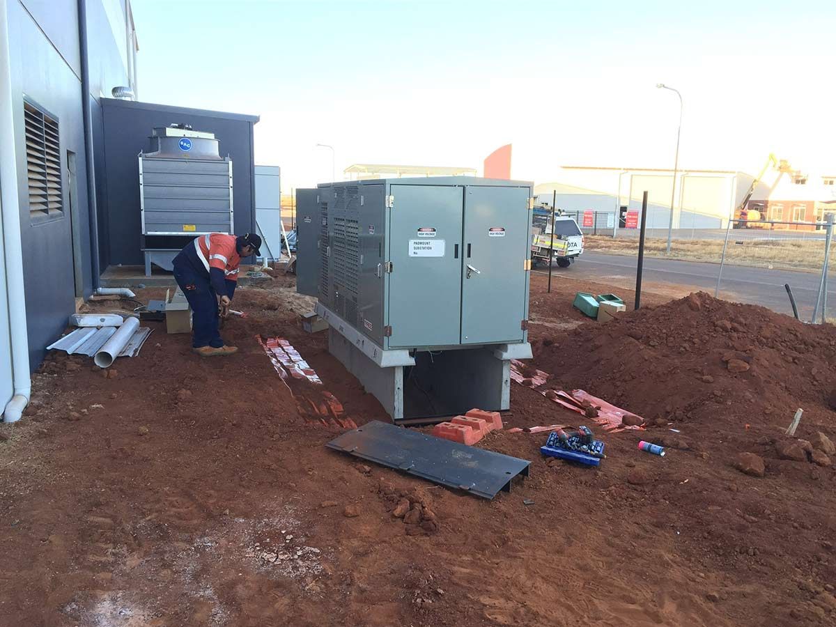A Man is Working on a Large Electrical Box in the Dirt — Country Powerline Constructions in Mudgee, NSW