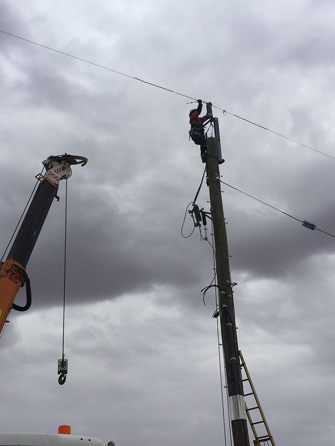 A Man is Standing on Top of a Power Pole Next to a Crane — Country Powerline Constructions in Dubbo, NSW