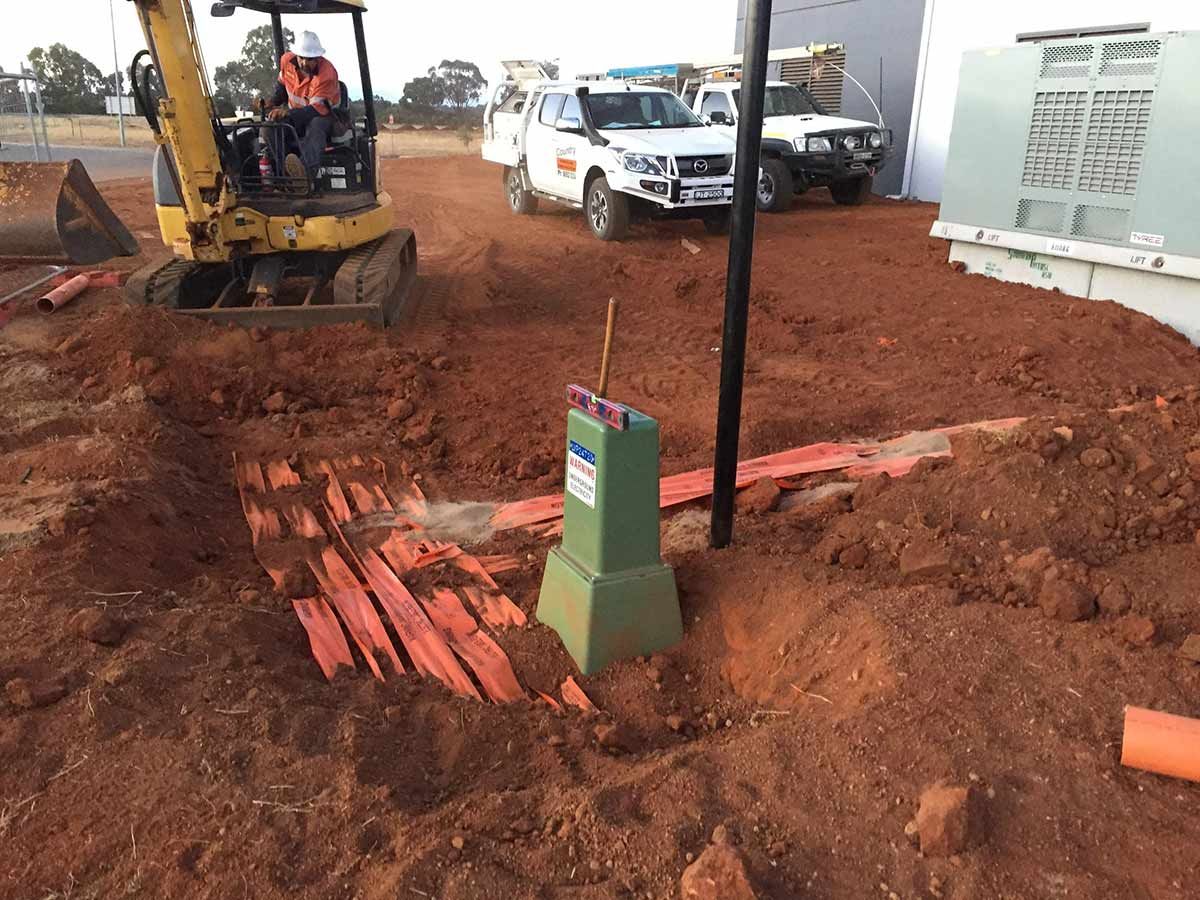 A Man is Driving a Yellow Excavator in a Dirt Field — Country Powerline Constructions in Dubbo, NSW