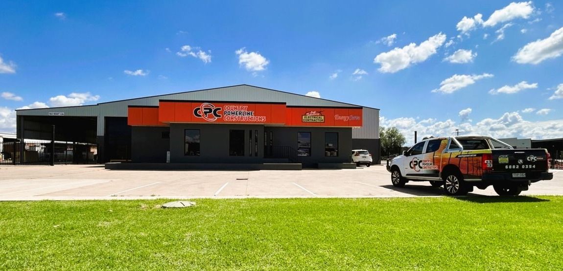 Small storefront with orange awning on a sunny day, black pickup truck parked on grass in front — Country Powerline Constructions in Dubbo, NSW