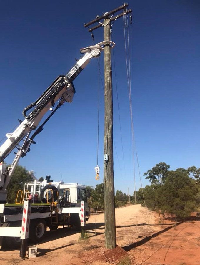 A Truck With a Crane Attached to It is Working on a Power Pole — Country Powerline Constructions in Dubbo, NSW