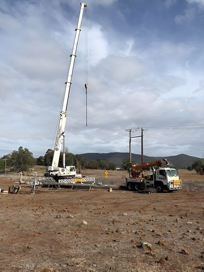 A Large Crane is Sitting on Top of a Truck in a Field — Country Powerline Constructions in Dubbo, NSW