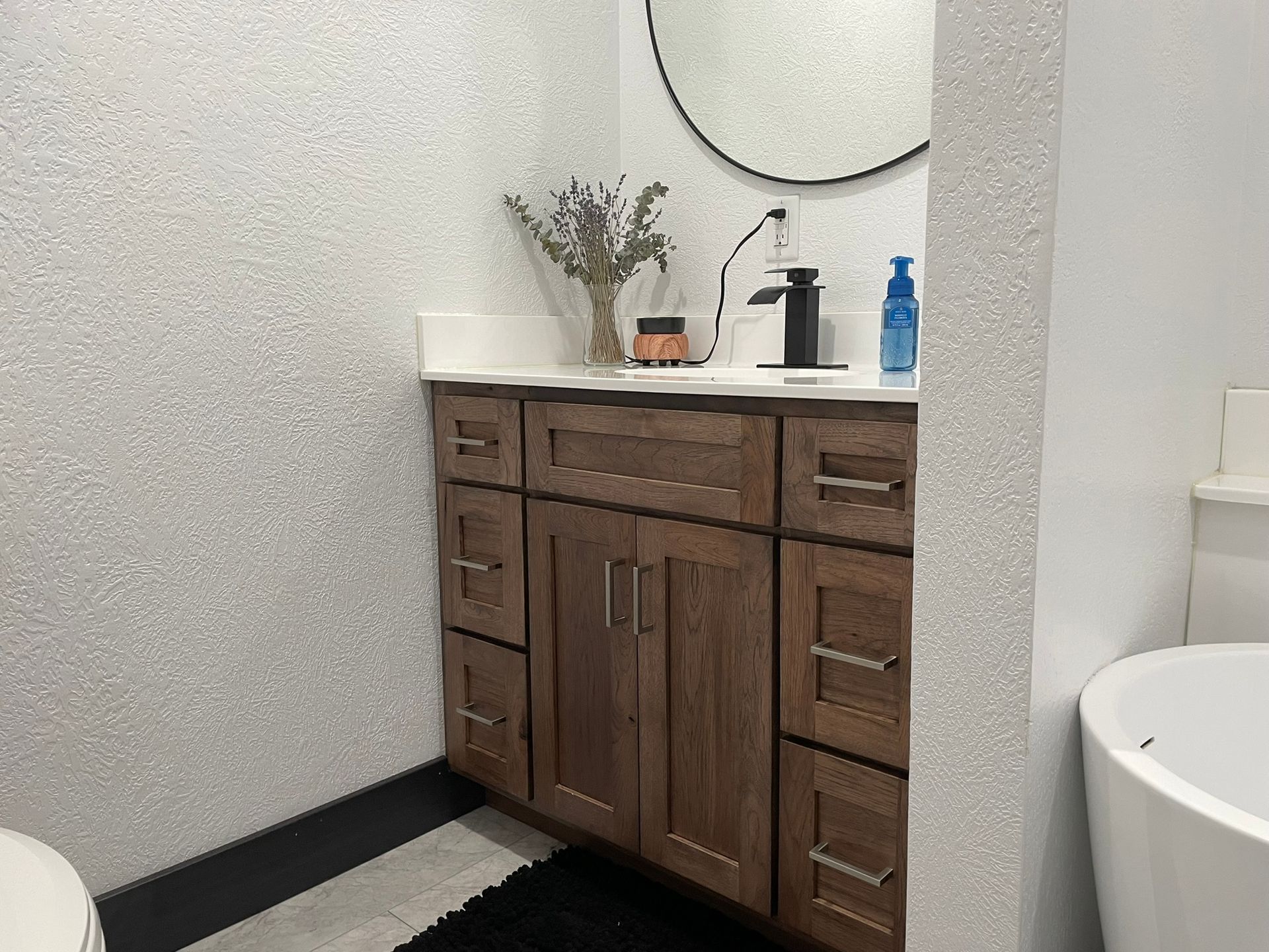Bathroom vanity with wood cabinets, double sinks, large mirror, and countertop items