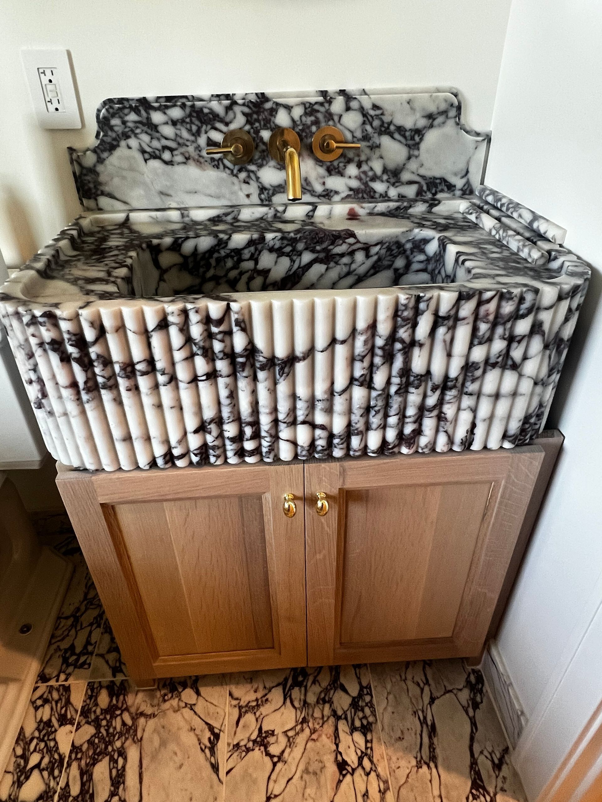 Bathroom sink cabinet with marble-look countertop and black-and-white decorative trim