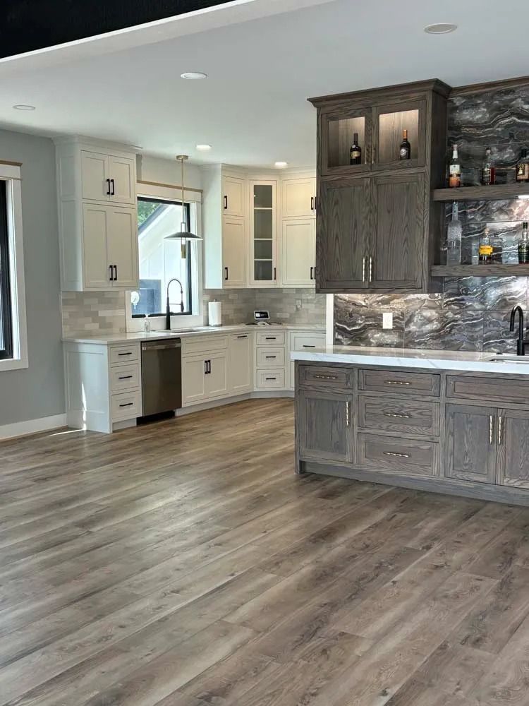 Modern kitchen with gray cabinets, stone backsplash, and wood flooring