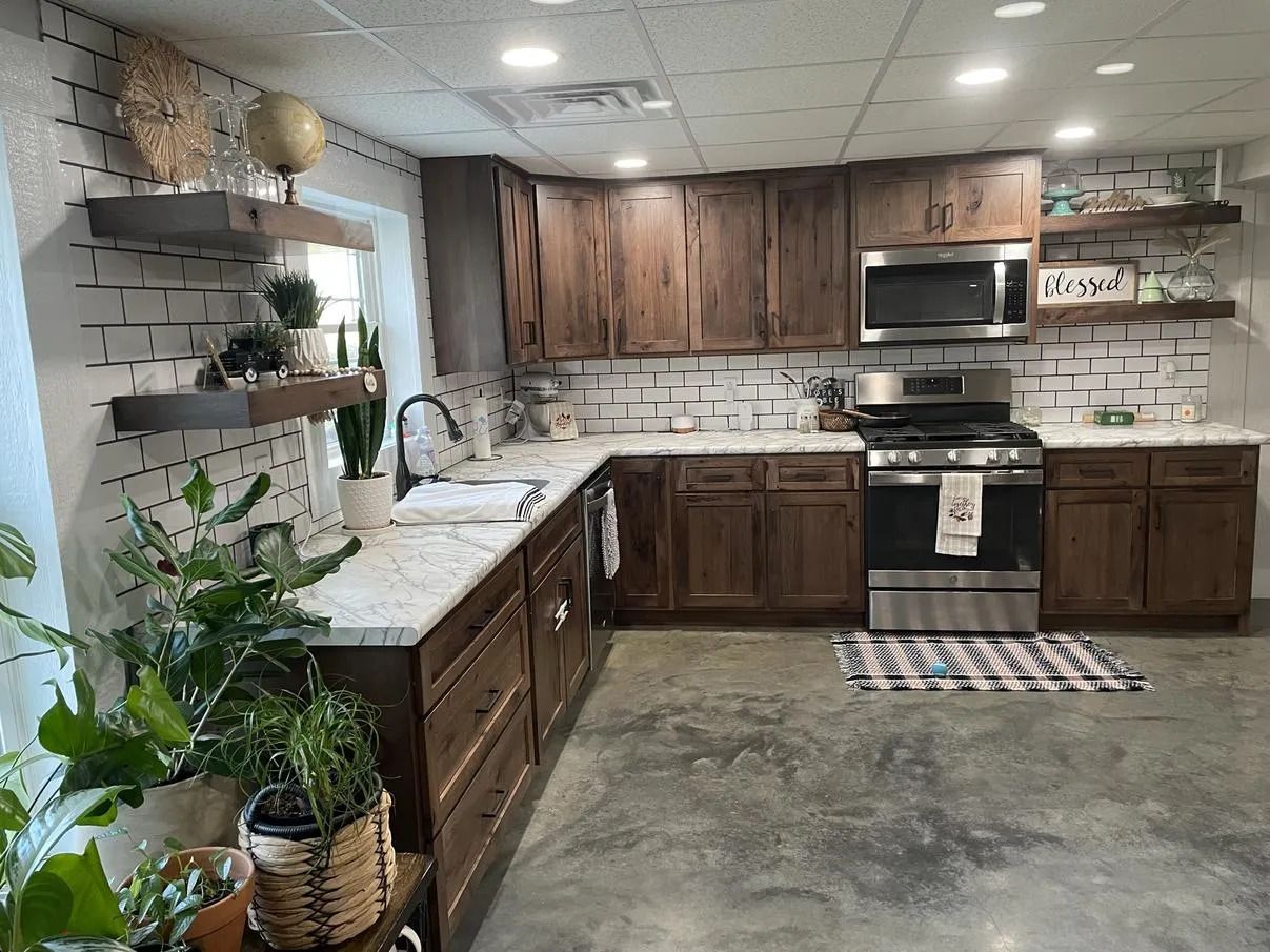 Modern kitchen with dark wood cabinets, white countertops, subway tile backsplash, and potted plants by the window