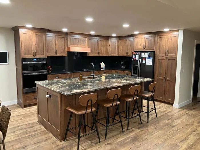 Modern kitchen with wood cabinets, granite island, bar stools, and stainless steel appliances