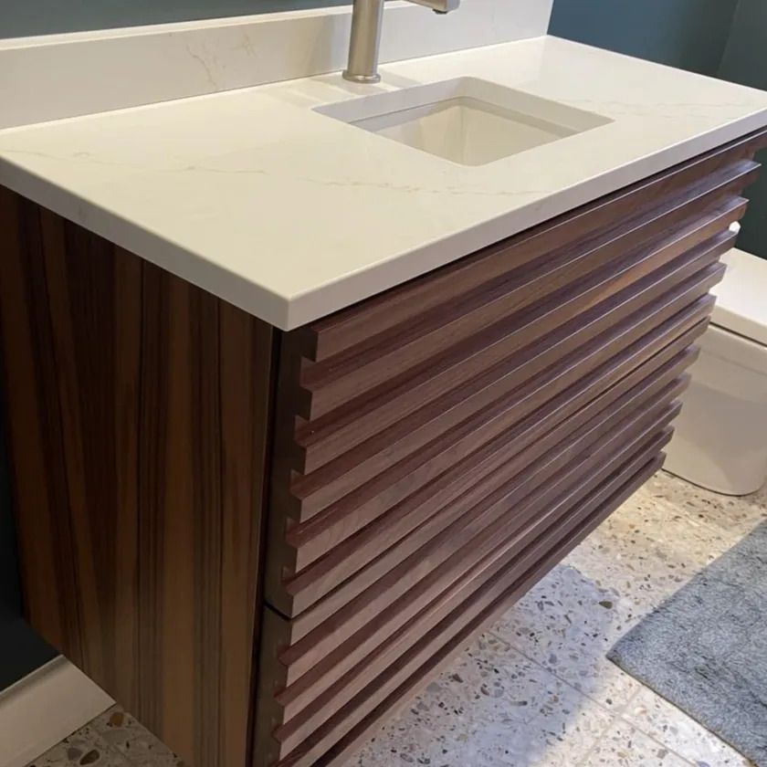 Modern bathroom vanity with white countertop, sink, and wood slat cabinet
