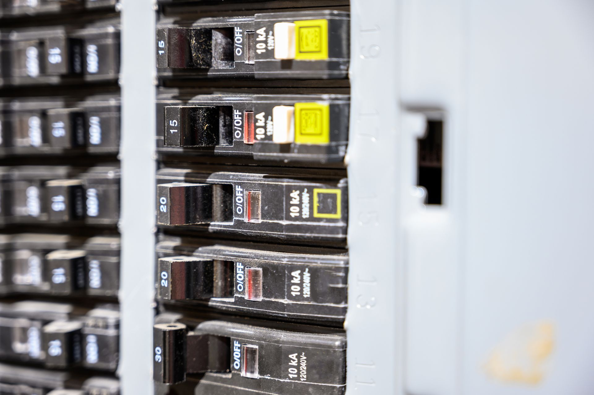 Row of black electrical circuit breakers with yellow switches in a utility panel cabinet Row of black electrical circuit breakers with yellow switches in a utility panel cabinet