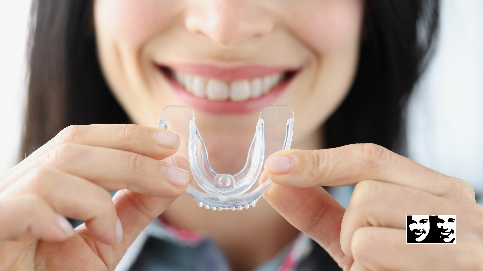 A woman is holding a mouth guard in front of her mouth.