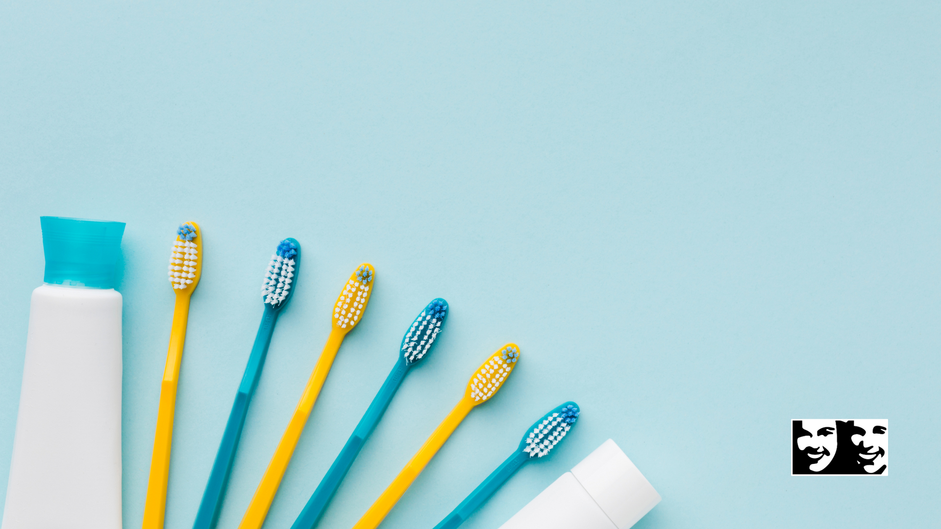 A row of toothbrushes and a tube of toothpaste on a blue background.