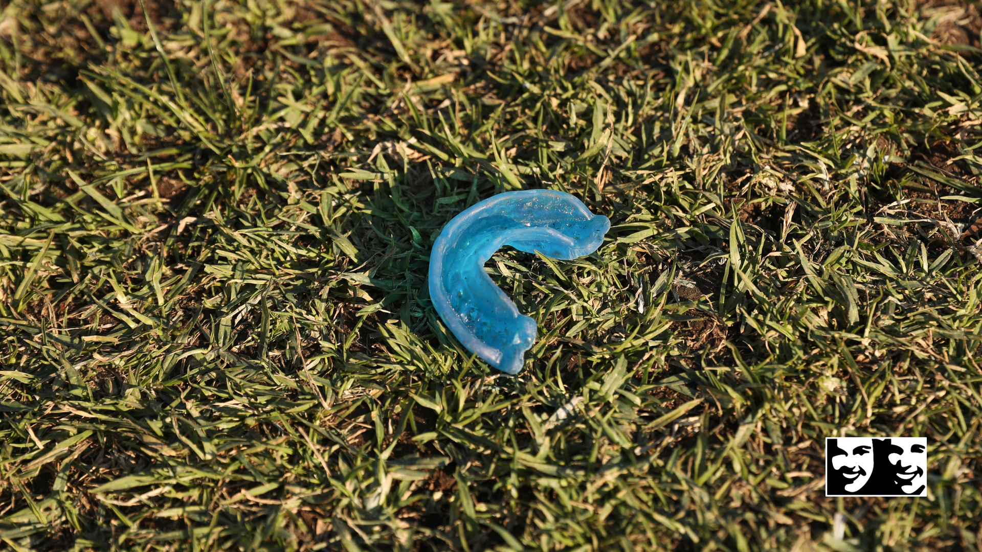 A blue mouth guard is laying in the grass.