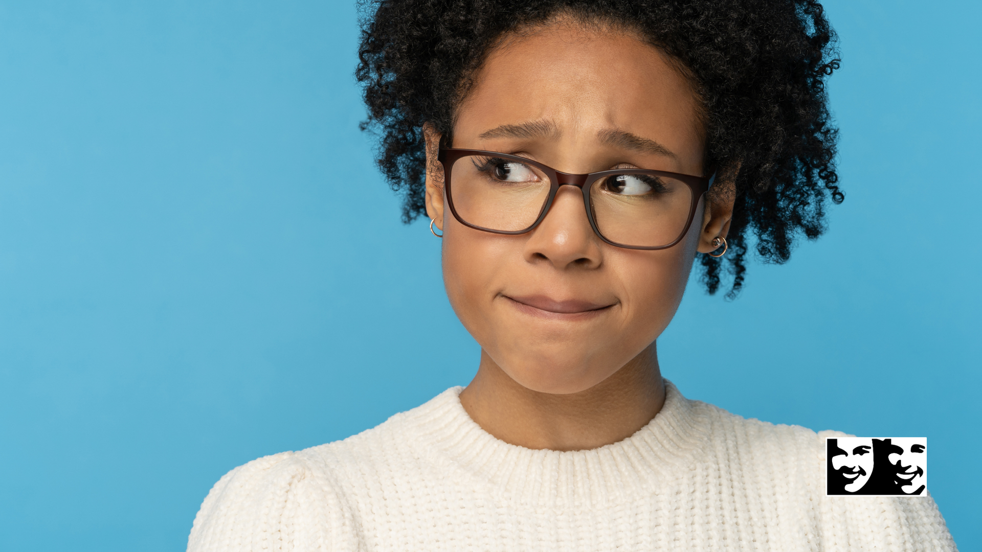 A woman wearing glasses and a white sweater is making a sad face.