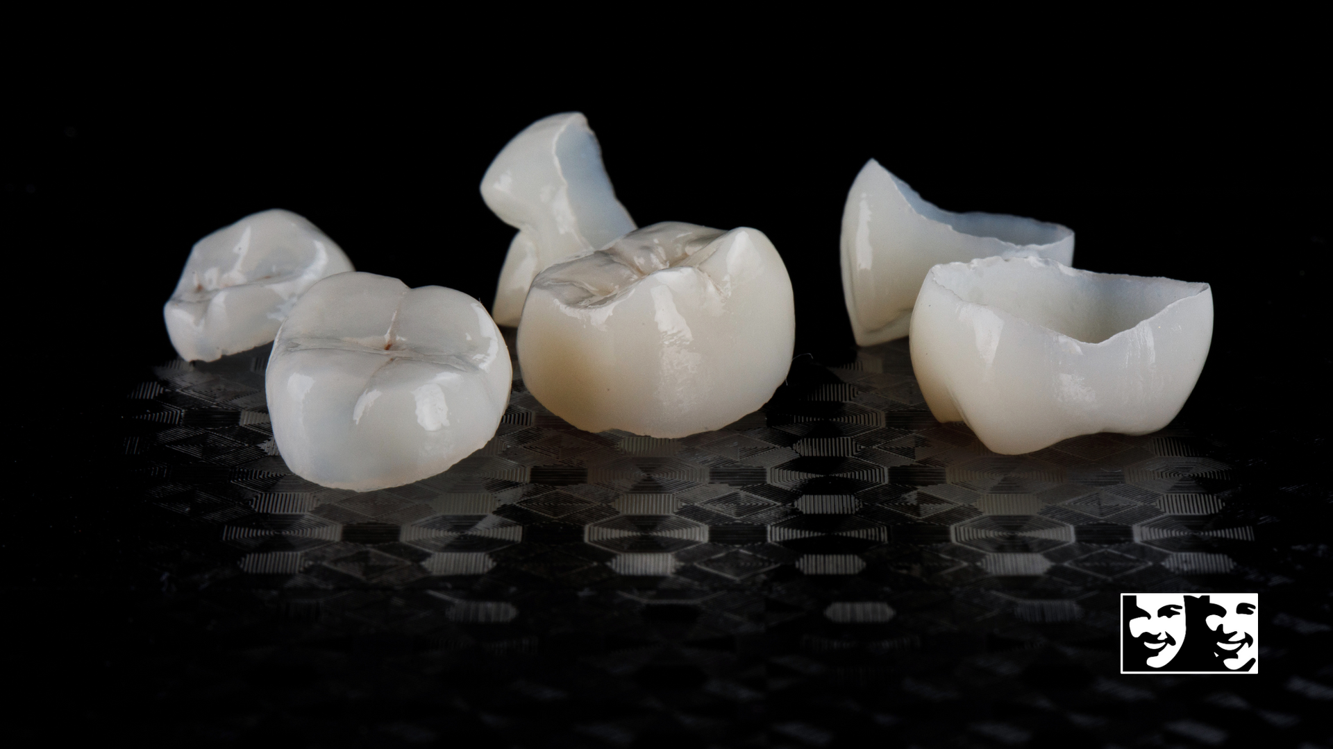 A group of dental crowns are sitting on a black surface.