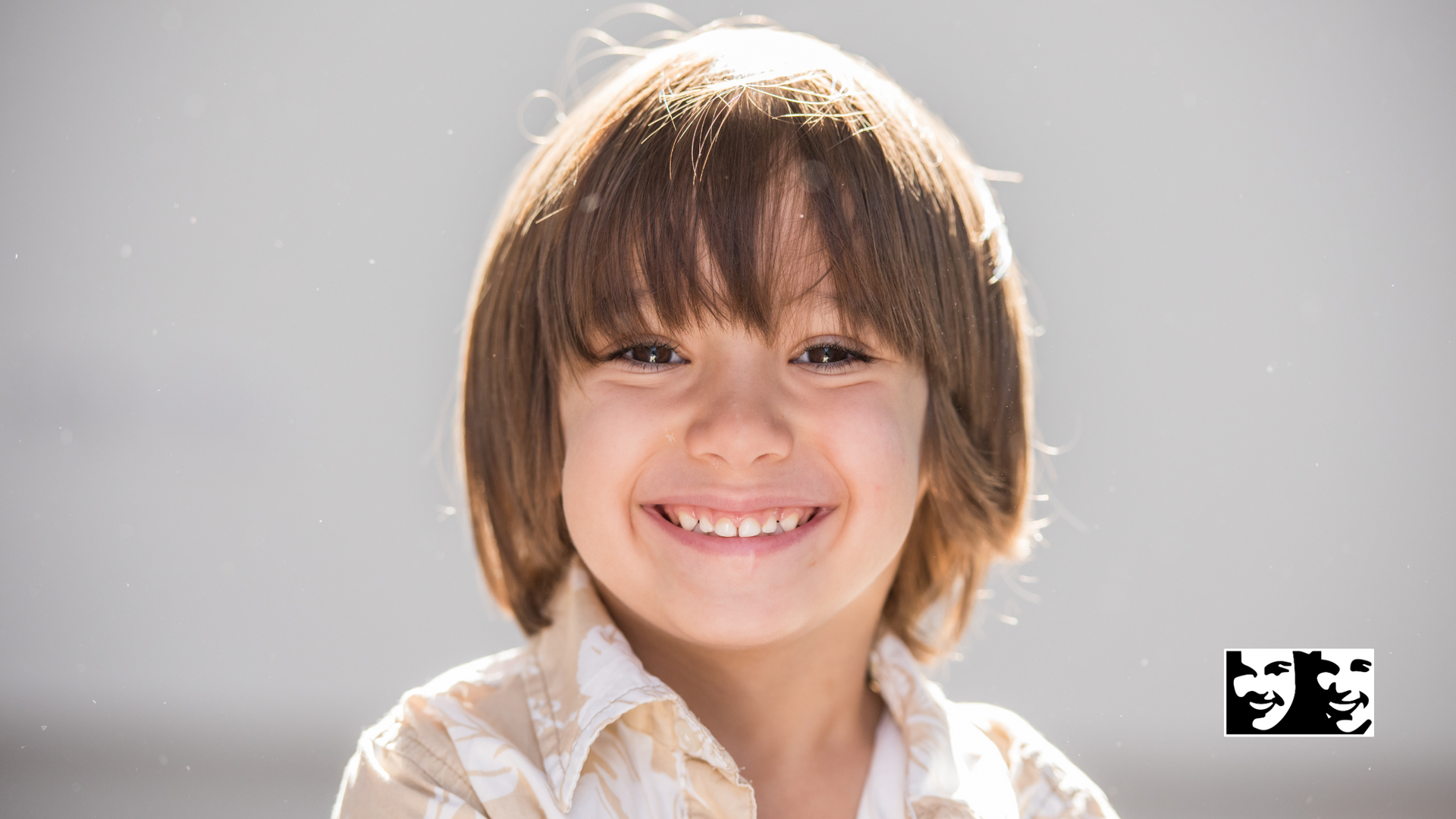 A young boy with long hair is smiling for the camera.