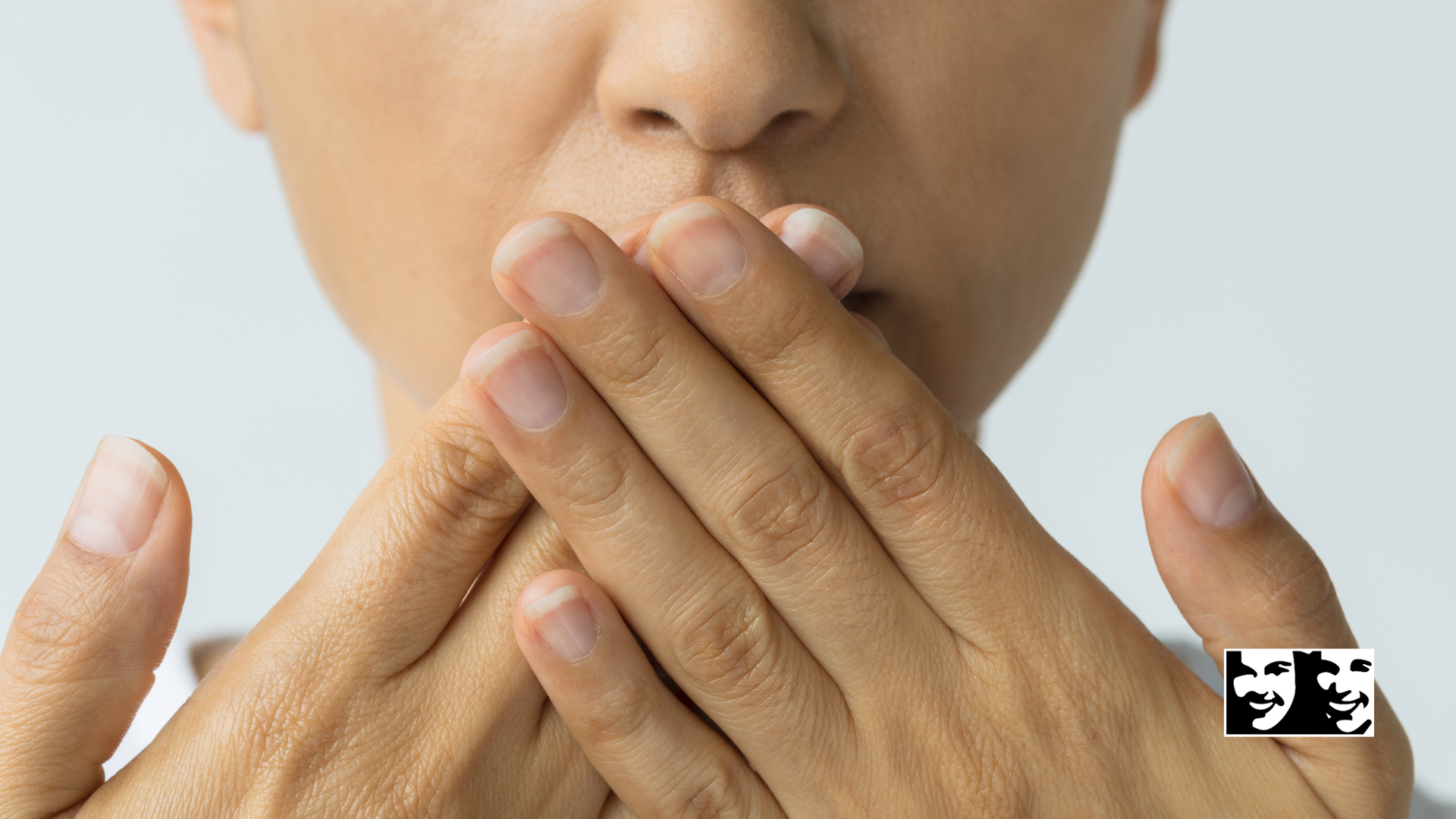 A woman is covering her mouth with her hands.